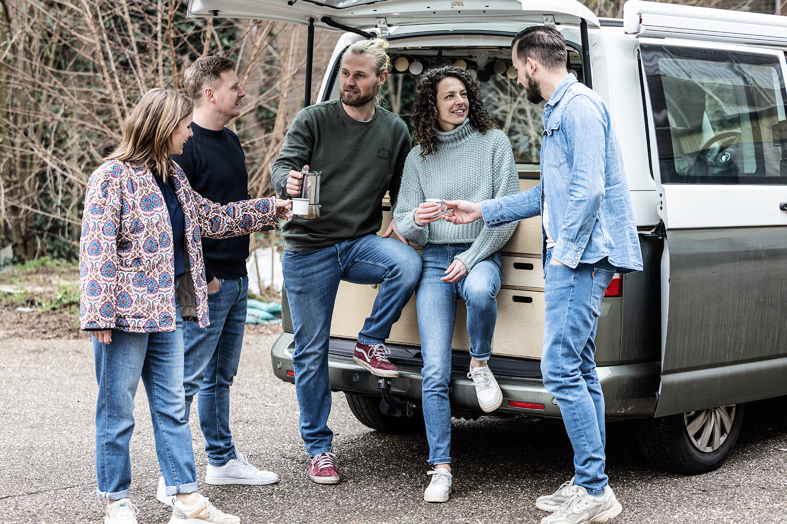 roep vrienden in Delft Denim jeans geniet van koffie bij een camper. Duurzame spijkerbroeken met tijdloos design, gemaakt van biologisch en gerecycled katoen.