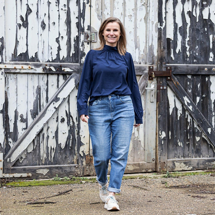 Vrouw draagt The Mom jeans van Delft Denim – een duurzame mom-fit spijkerbroek met hoge taille en relaxte pasvorm. Gemaakt van biologisch en gerecycled katoen.
