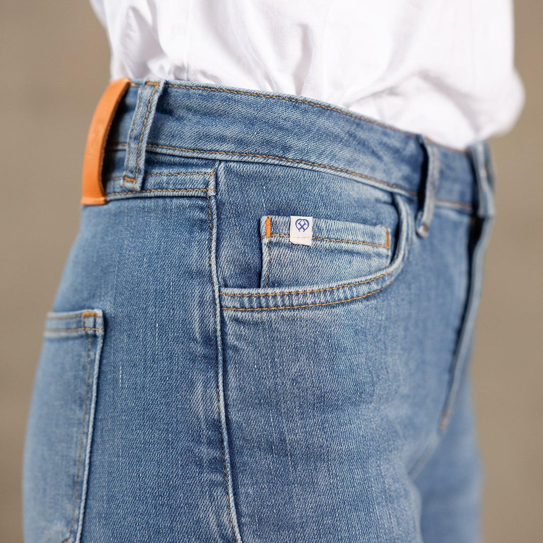 Zijaanzicht van een model in The Skinny jeans van Delft Denim – een duurzame skinny-fit dames spijkerbroek. Detail van coin pocket met logo, biologisch en gerecycled katoen.